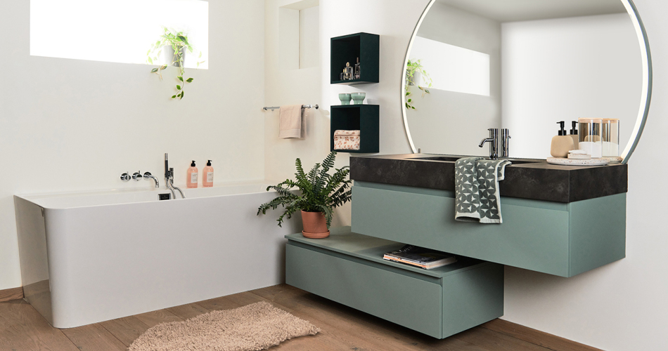 Badkamer met blauw-groen meubel en grote ronde spiegel toonzaal turnhout